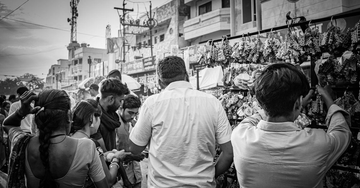 A vibrant black and white shot of a busy street market, showcasing diverse people shopping.